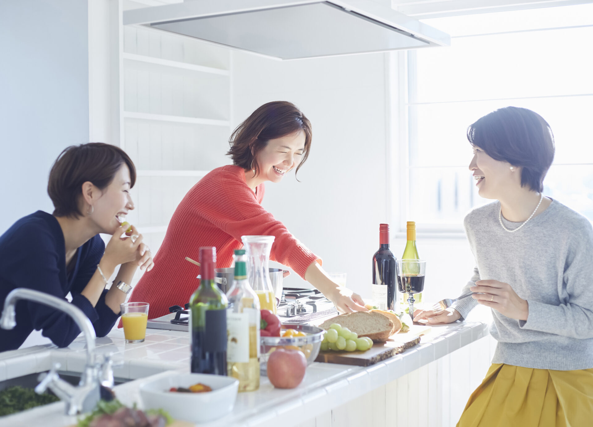 対面式キッチンで会話する女性の画像